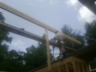 Carpenter setting a ridge beam over a new addition frame — Ice Dam Removal by Roofing Brothers in Wells River