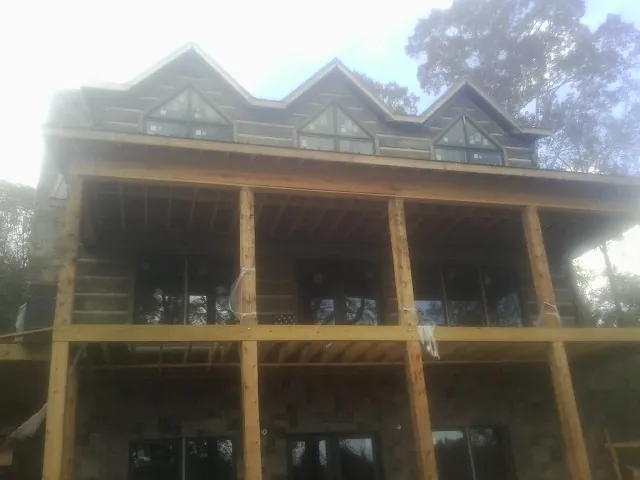Dormers and porch framing on a large log home under construction — Roof Coating work by our crew in Wells River