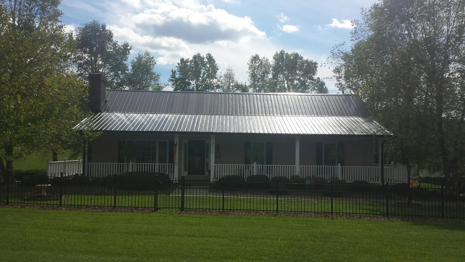 Gray metal roof on a brick ranch with a full width front porch — Gutter Guard Installation work by our crew in Wells River