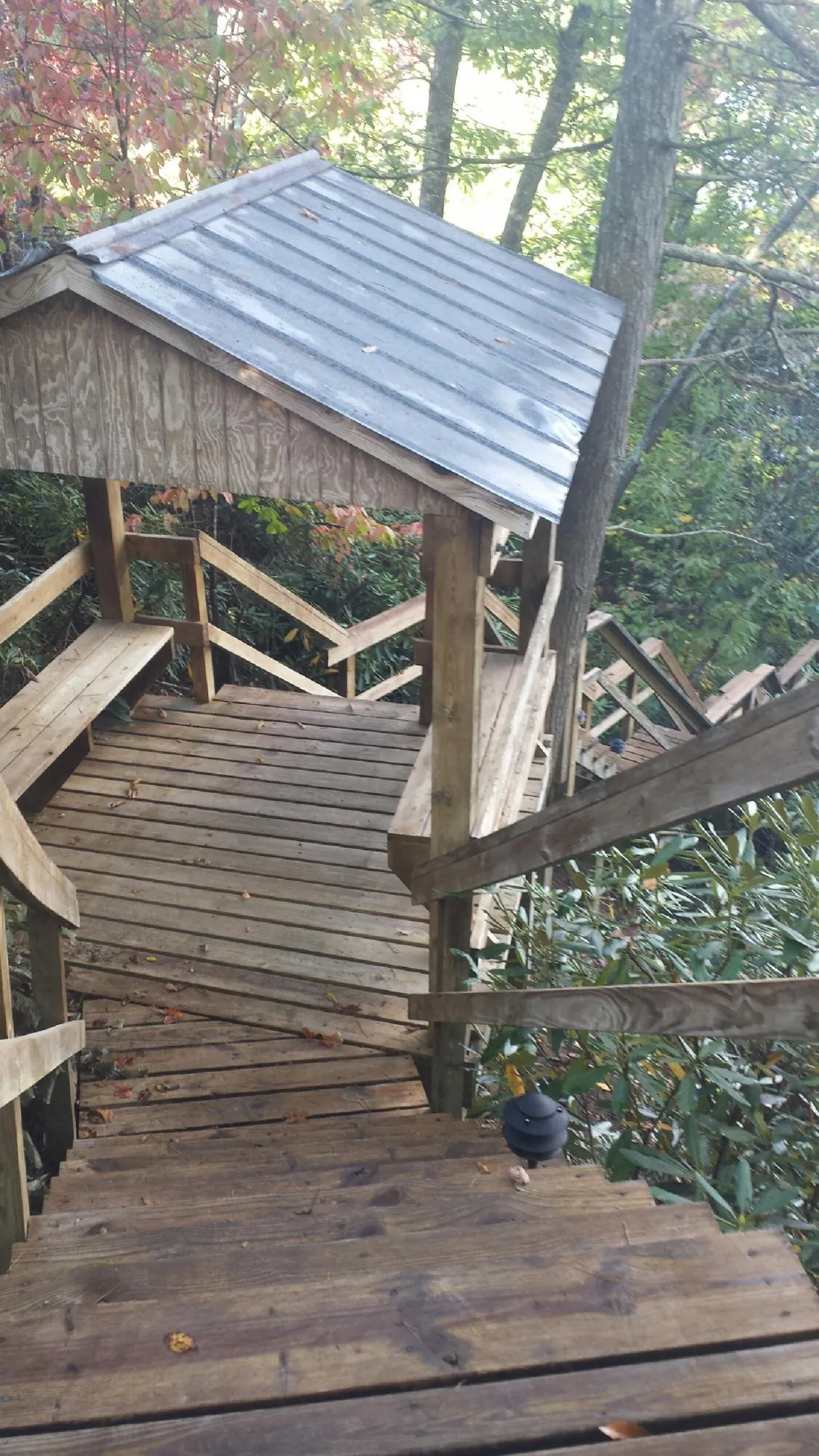 Metal roofed shelter over wooden steps on a wooded walkway — Skylight Repair & Installation work by our crew in Wells River