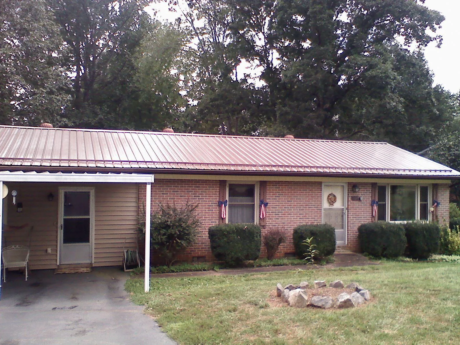Bronze metal roof and carport on a brick ranch home — Roof Repair work by our crew in Wells River