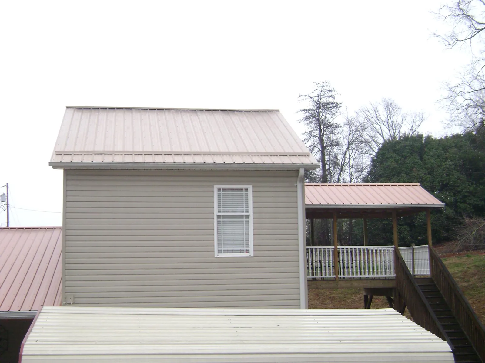 Tan metal roofs on a two story addition and attached porch, from a Roof Replacement job in Wells River