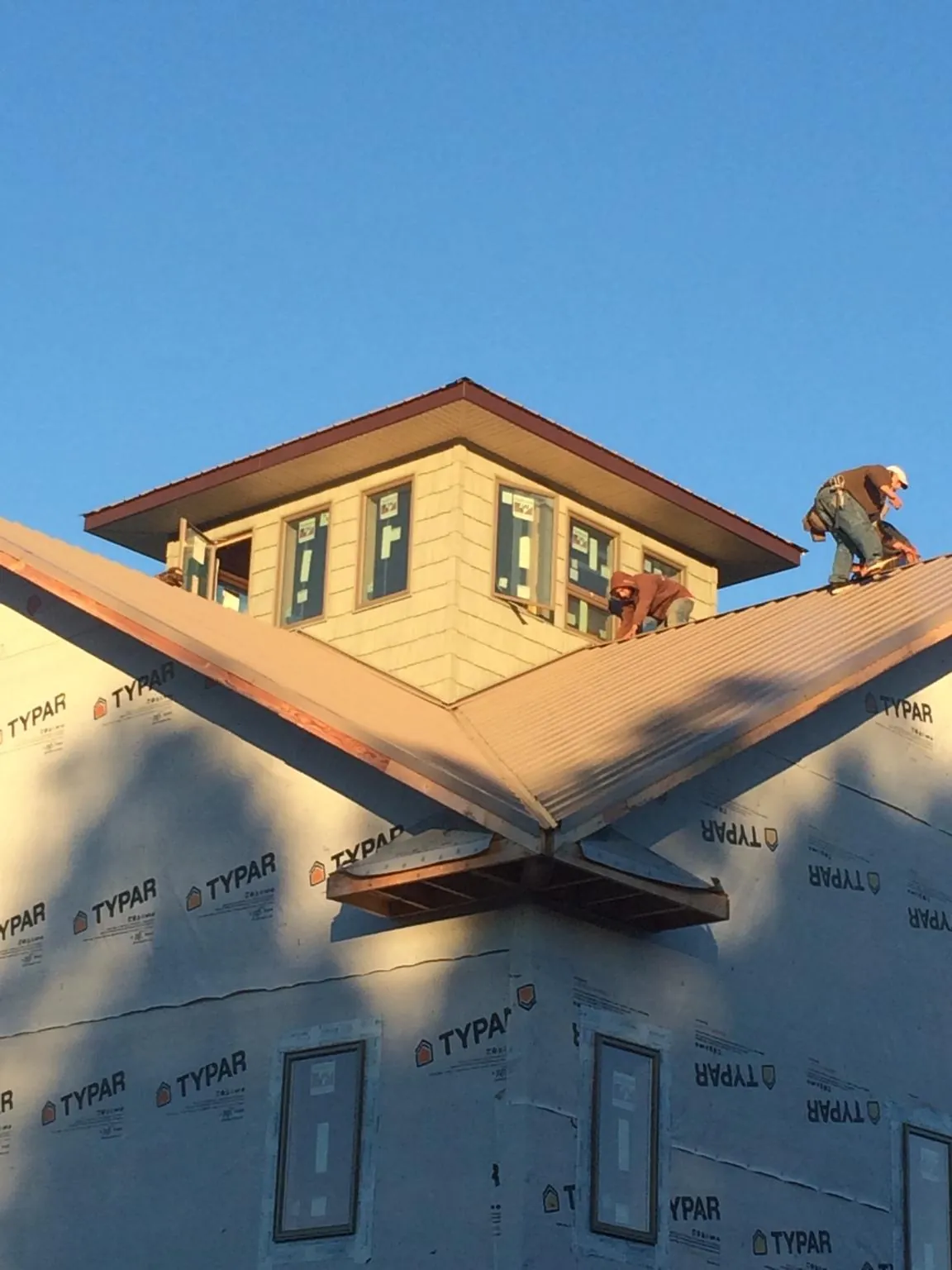 Roofers working around a rooftop cupola on a new metal roof at sunset — Roof Waterproofing in Wells River by Roofing Brothers